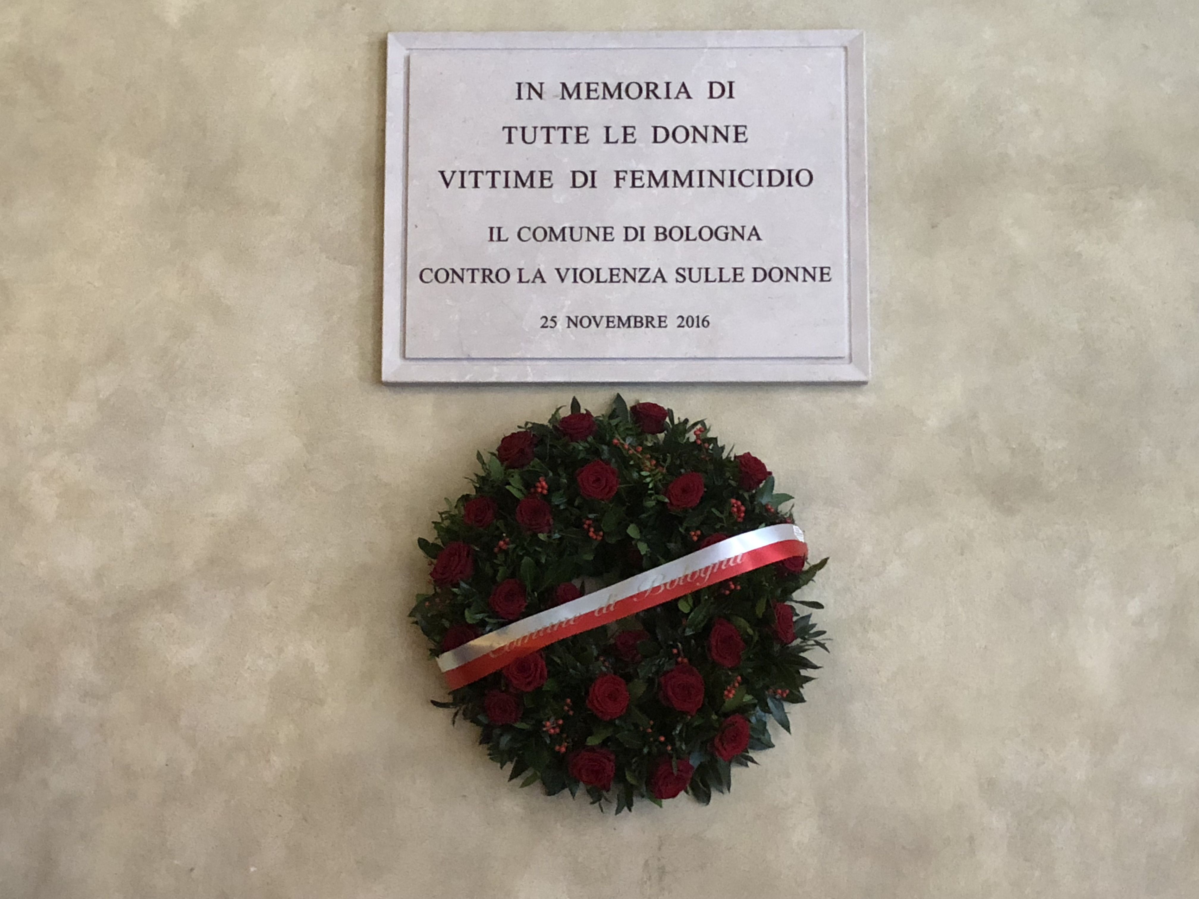 Corona di fiori alla targa in memoria vittime femminicidio